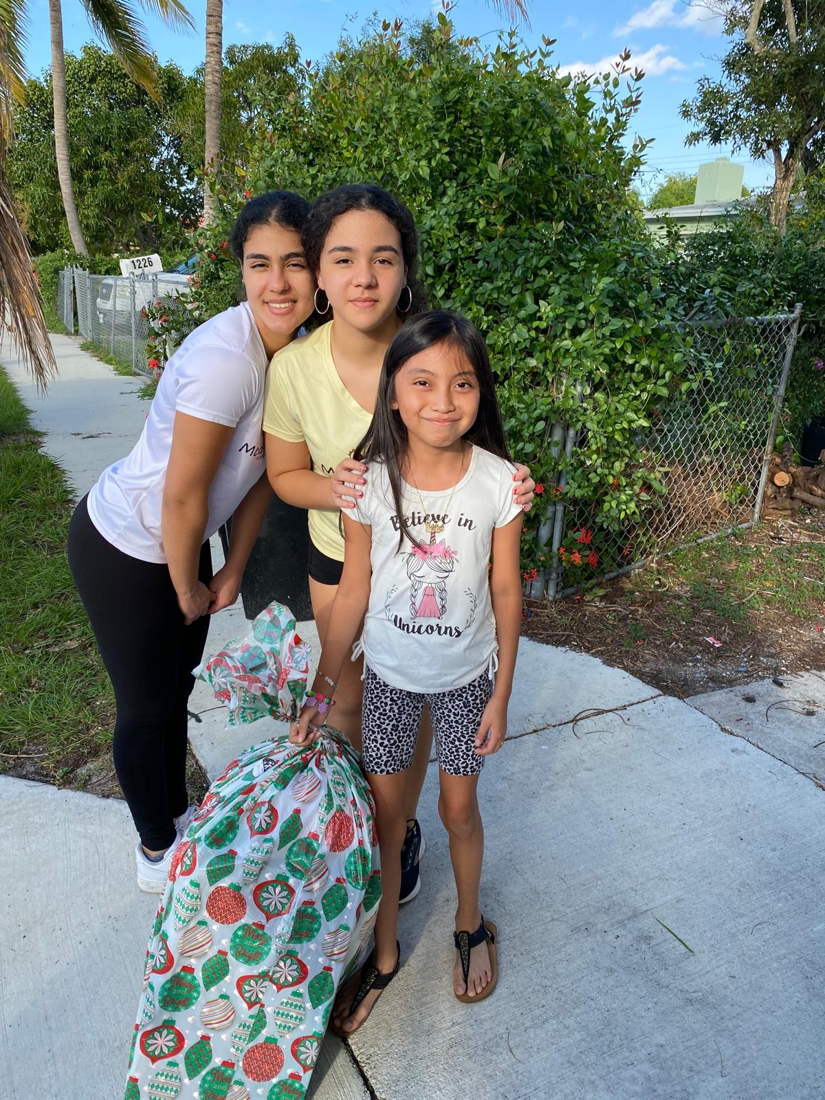 Dani and Ariela embracing girl on sidewalk